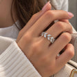 Hand wearing a silver leaf vine ring with marquise crystals, over a cream knit sleeve
