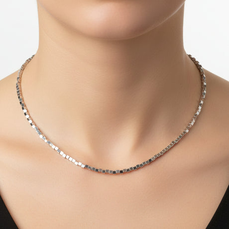 Silver cube necklace worn by a woman on a white background