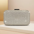 Silver clutch bag with rhinestone embellishments on a beige surface