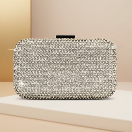 Silver clutch bag with rhinestone embellishments on a beige surface