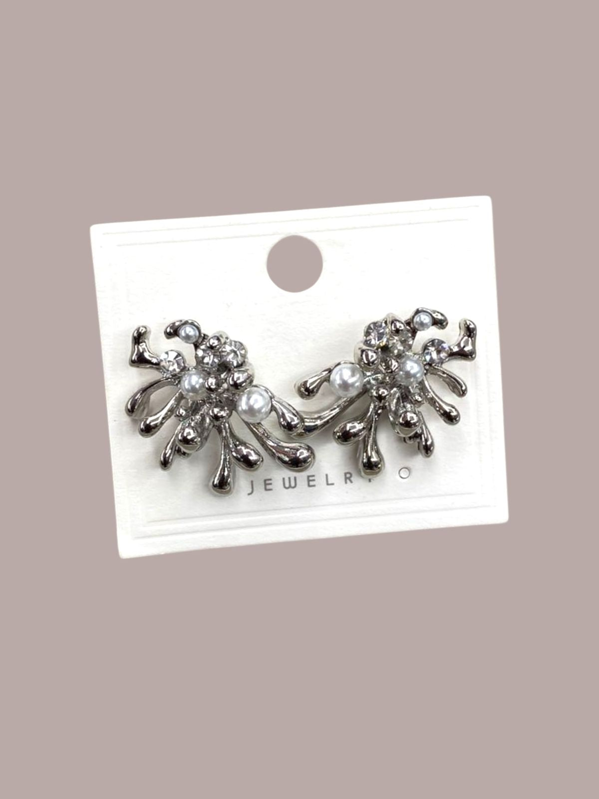 Pair of silver modern earrings with pearls on a jewelry card against a beige background