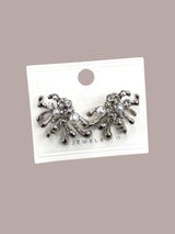 Pair of silver modern earrings with pearls on a jewelry card against a beige background