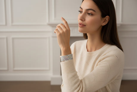 Woman in a beige sweater with decorative silver bracelets, and fireplace in the background