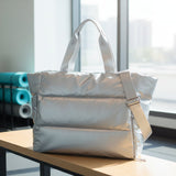 Silver puffer tote bag on a wooden bench showing the quilted padded texture