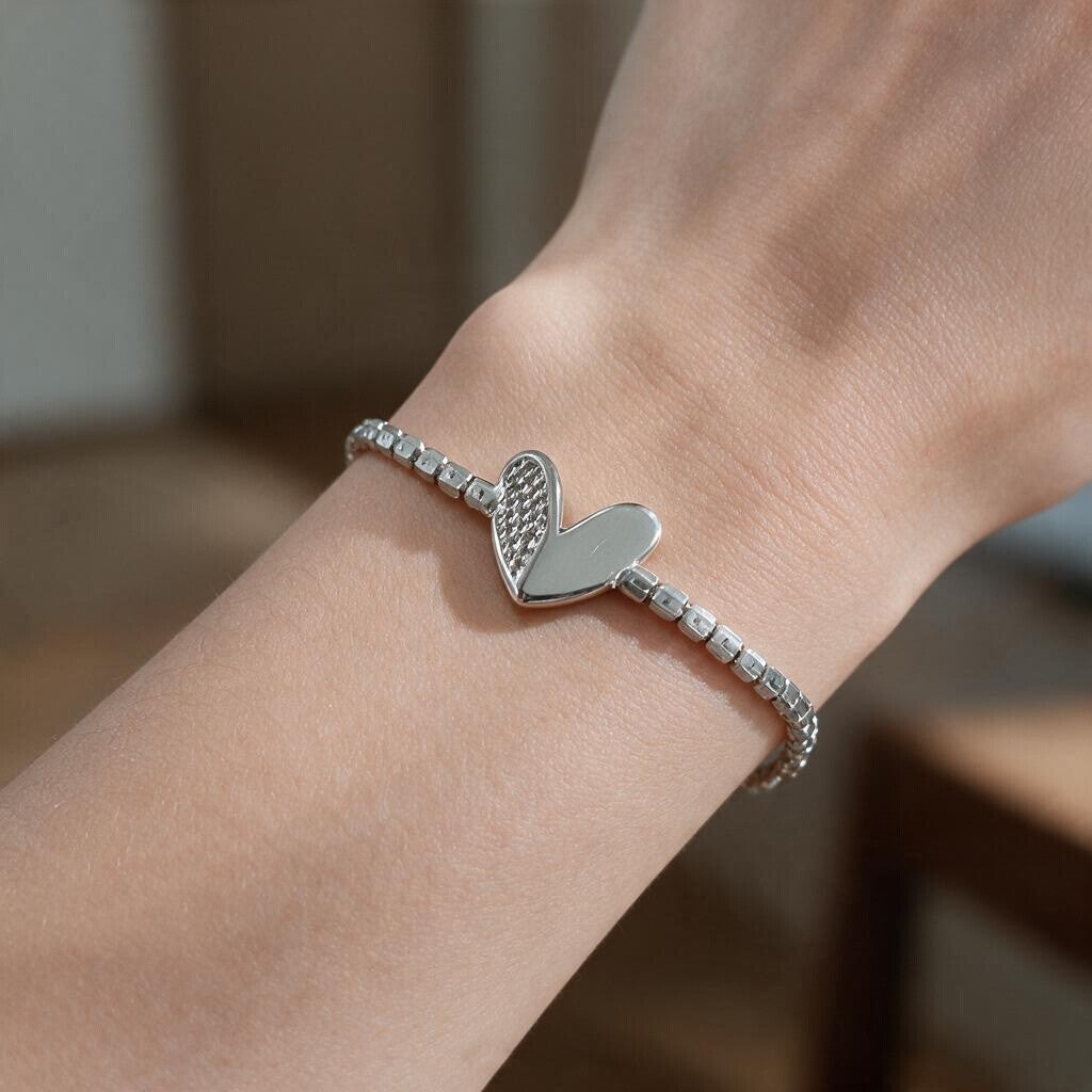 Silver tennis bracelet with a heart charm, half crystal and half polished, on the wrist