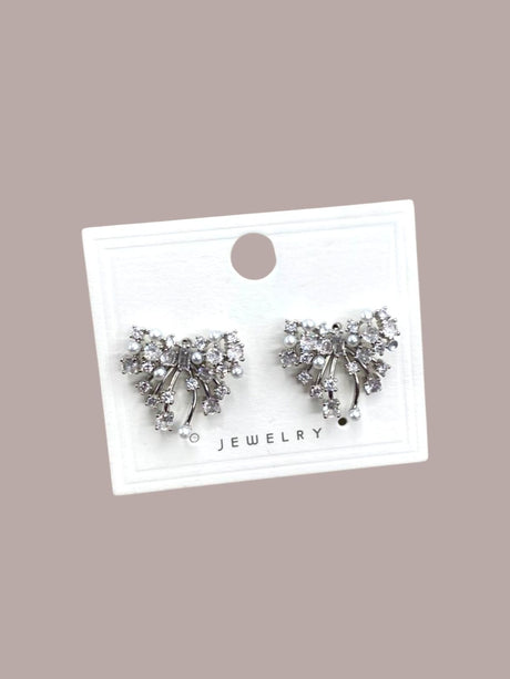 Pair of silver bow-shaped earrings on a white card with 'Jewelry' text against a beige background
