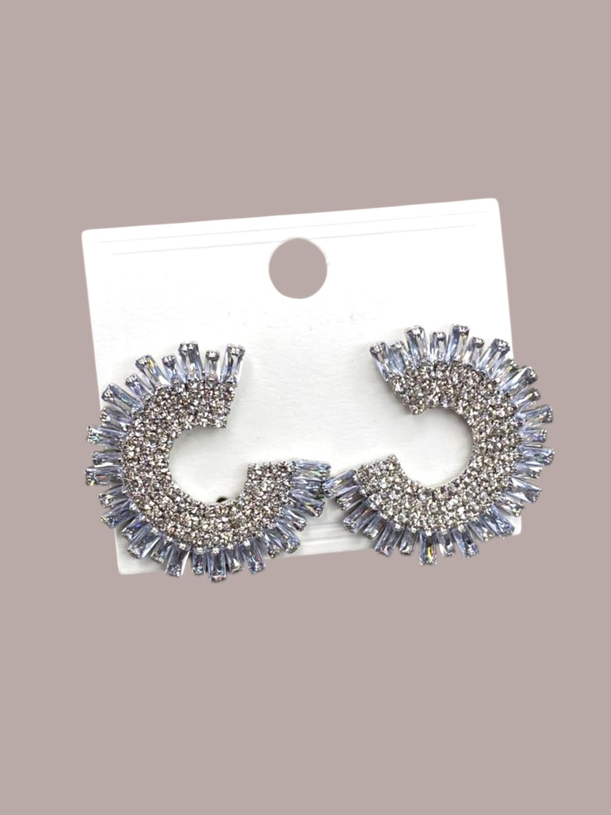 Pair of silver spikey earrings on a white card against a beige background