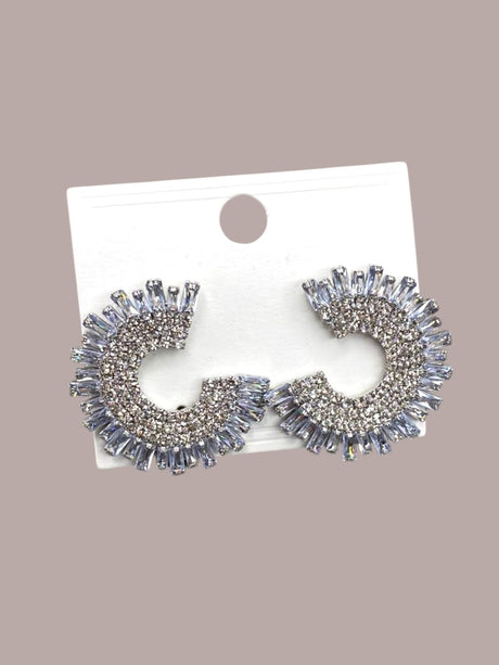 Pair of silver spikey earrings on a white card against a beige background