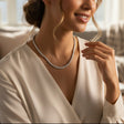 Woman wearing a pearl necklace in a cozy living room setting