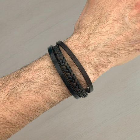 Black braided leather bracelet on a wrist against a neutral background