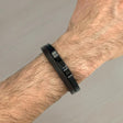 Black & brown bracelet on a wrist against a grey background