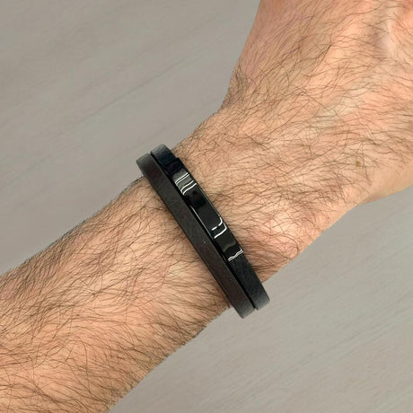 Black & brown bracelet on a wrist against a grey background