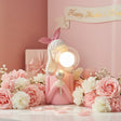 Blonde singer figure with her silver microphone banked in roses and carnations