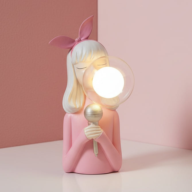 Long blonde hair, a knotted pink bow and a chrome microphone under a lit glass globe