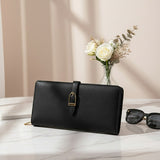 Black leather wallet on a white surface with a vase of flowers and sunglasses in the background