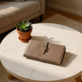 Brown wallet on a marble coffee table with a potted plant