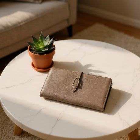 Brown wallet on a marble coffee table with a potted plant