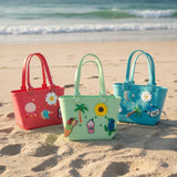 Coral red, mint green and turquoise waterproof tote bags with palm and daisy charms by the shore