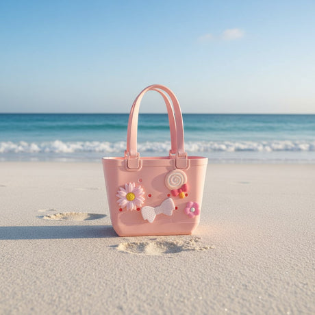 Peachy pink kids tote standing on bright white sand with clear blue sky and turquoise water behind