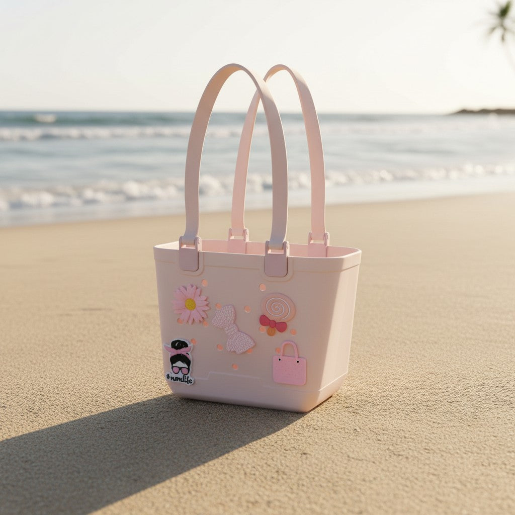 Pale pink rubber beach tote with matching handles and daisy, bow, lollipop and handbag charms