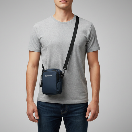 Person wearing a small blue crossbody bag with a visible brand logo on a grey background
