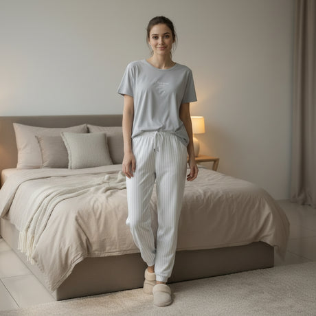 Woman wearing grey short-sleeve top and striped full-length pants pyjama set in bedroom - Jack Gifts Lebanon