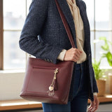 Burgundy bag worn crossbody over a navy tweed blazer and cream blouse
