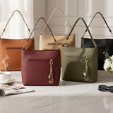 Five shoulder bags grouped on marble in tan, cream, burgundy, olive and black