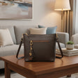 Dark brown shoulder bag with gold hardware and a tassel charm on a wooden coffee table