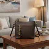 Dark brown shoulder bag with gold hardware and a tassel charm on a wooden coffee table