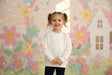 Girl in a cream sweatshirt with scattered rhinestones and navy pants