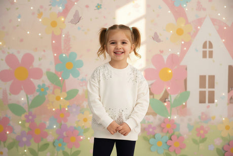 Girl in a cream sweatshirt with scattered rhinestones and navy pants