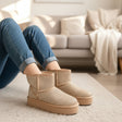 Person wearing beige snow boots with a blurred background of a living room.
