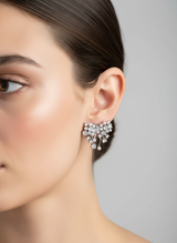 Close-up of a woman wearing a sparkling bow-shaped earring against a neutral background