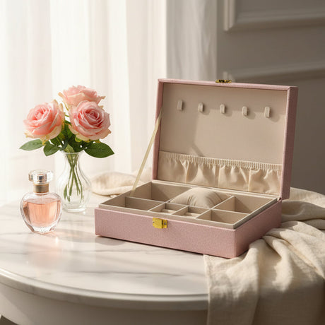 Pink glitter jewelry box open with a cream lined tray, elastic pocket and ring cushion