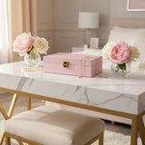 Blush pink glitter jewelry box with an ornate gold clasp and gold chains draped over it