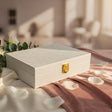 Ivory white glitter jewelry box with a gold push clasp resting on cream satin