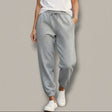 Person wearing gray sparkly sweatpants with small embellishments on a plain background