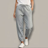 Person wearing gray sparkly sweatpants with small embellishments on a plain background
