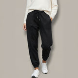 Person wearing black sparkly sweatpants and white sneakers on a plain background