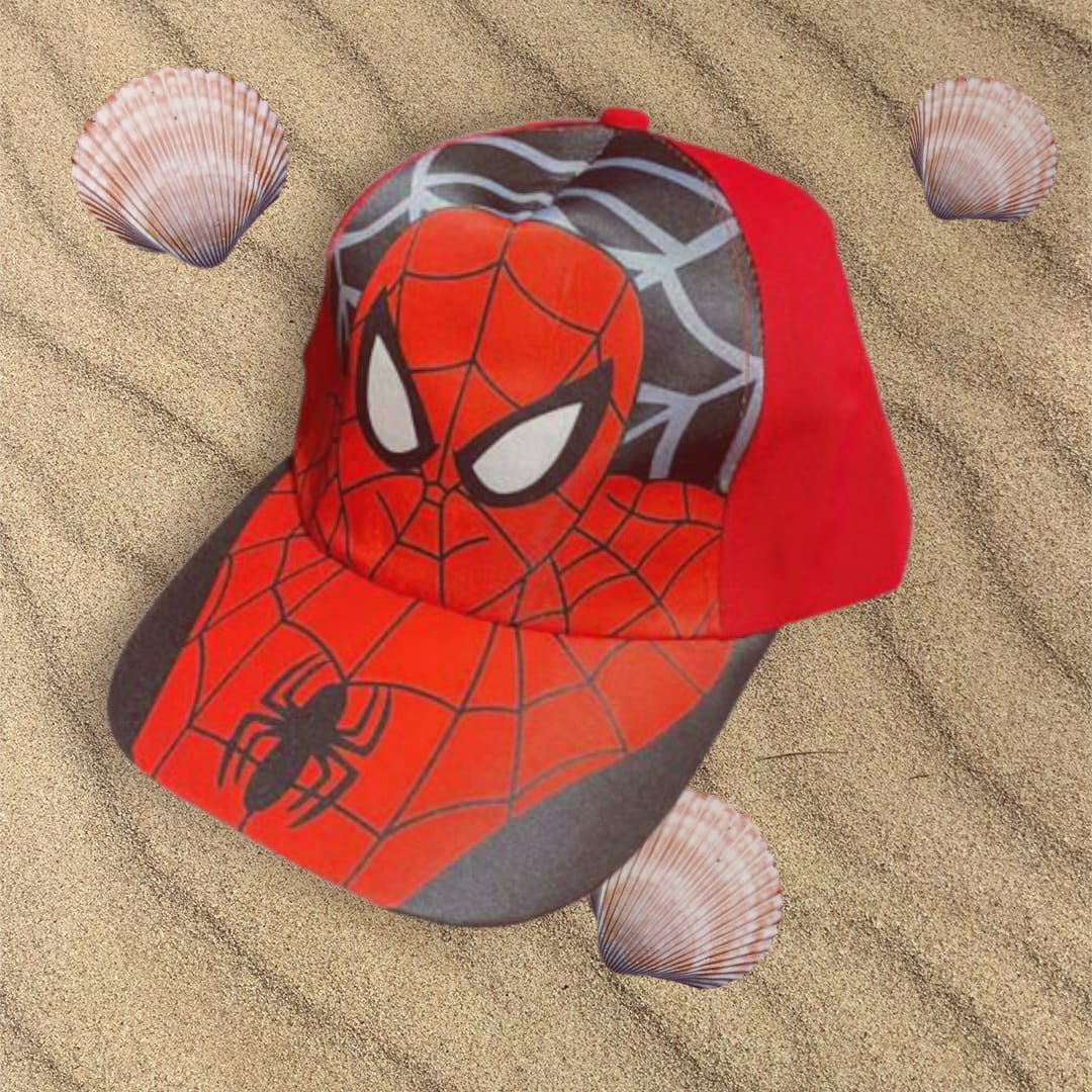Red and grey childrens cap with a spider emblem and web design on the peak, resting on sand