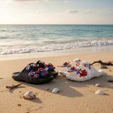 Black and white kids double band slides with Spiderman charms on a sunny beach