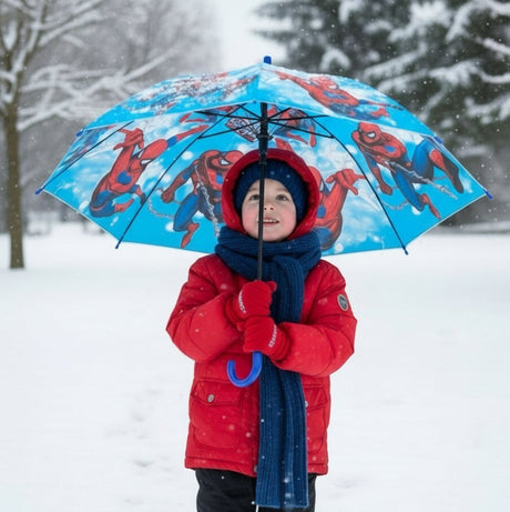 Boy in snow holding an open bright blue Spiderman kids umbrella with a red hero print