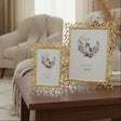 Two gold frames built from cast twigs and spikes, beside a vase of dried pampas
