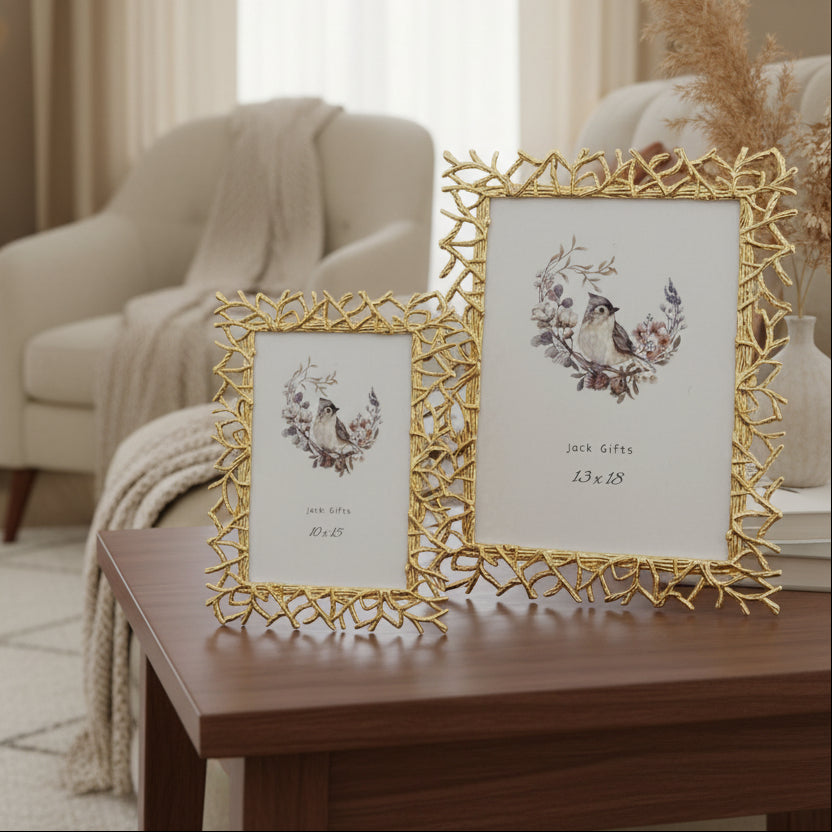 Two gold frames built from cast twigs and spikes, beside a vase of dried pampas