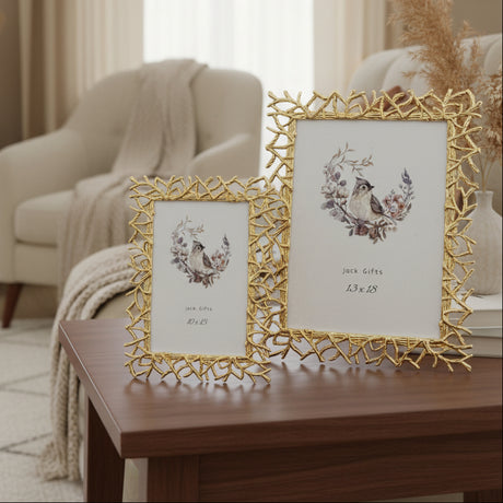 Two gold frames built from cast twigs and spikes, beside a vase of dried pampas
