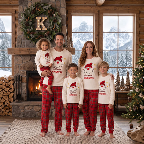 Family in matching Santa pyjamas in front of a stone fireplace in a snowy cabin