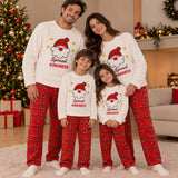 Parents and two children in matching Spread Kindness Santa pyjamas in a festive living room