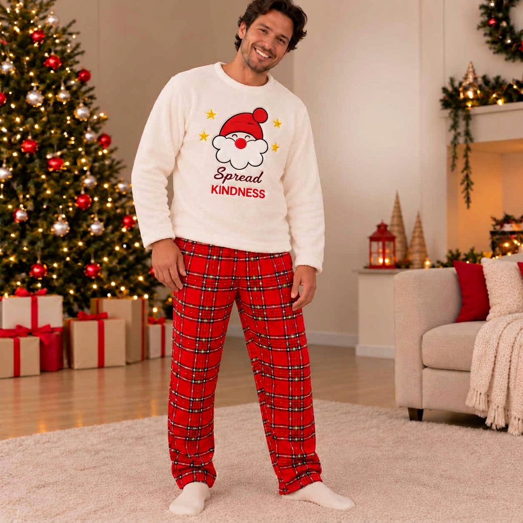 Man in cream Spread Kindness Santa fleece top and red plaid pyjama pants in a festive living room