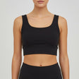 Woman wearing a black athletic top and leggings on a plain background